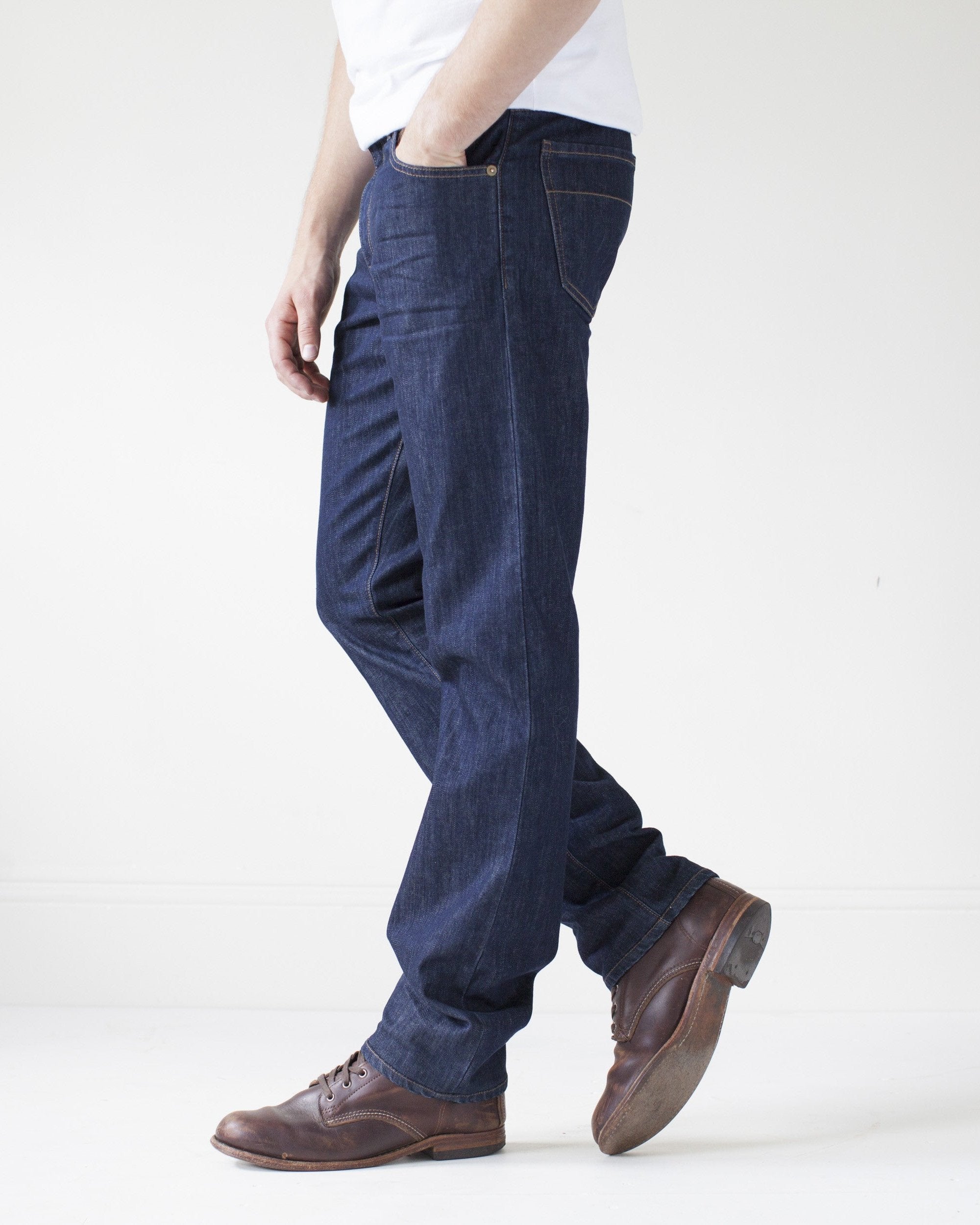 angle: resin rinse | A model wears Raleigh Denim Workshop Alexander work fit jeans with a dark wash, side view