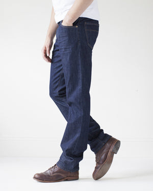 angle: resin rinse | A model wears Raleigh Denim Workshop Alexander work fit jeans with a dark wash, side view